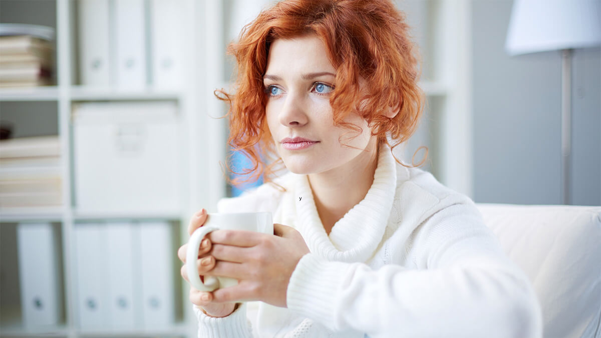 Woman thinking while holding tea cup