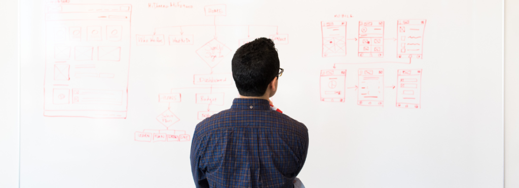 man looking at whiteboard with plans